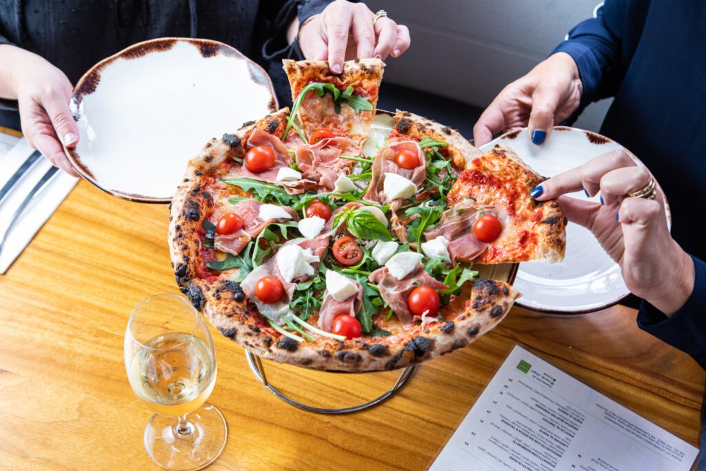 Guests sharing wood-fired prosciutto pizza at Il Verde Italian restaurant on King Street in Bowen Hills Brisbane