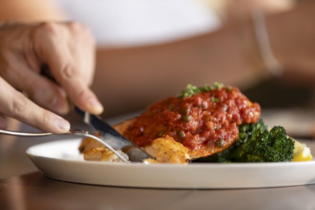 Guest cutting into salmon with tomato sugo at Il Verde Italian restaurant on King Street in Bowen Hills Brisbane