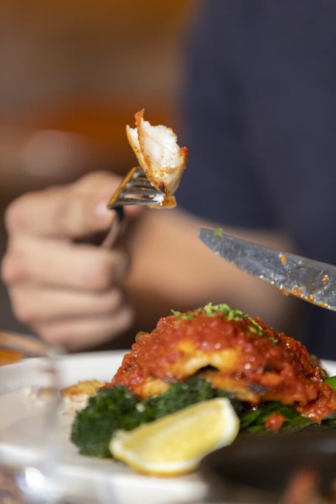 Guest cutting into seafood entrée with tomato sugo at Il Verde Italian restaurant on King Street in Bowen Hills Brisbane