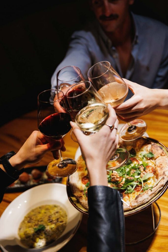 Friends toasting wine over pizza at Il Verde Italian restaurant on King Street in Bowen Hills Brisbane