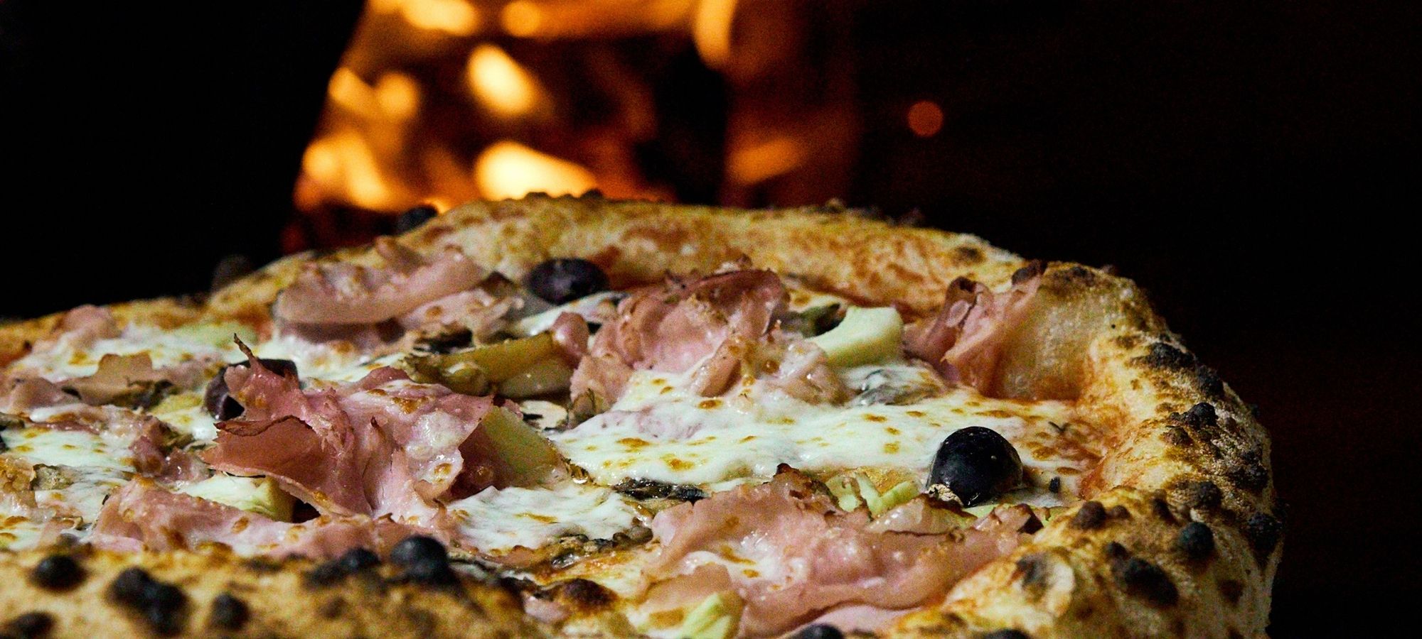 Wood-fired prosciutto pizza with olives and mozzarella at Il Verde Italian restaurant in Bowen Hills Brisbane