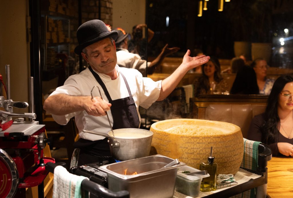 Chef presenting pasta beside a Grana Padano cheese wheel at Il Verde in Bowen Hills Brisbane