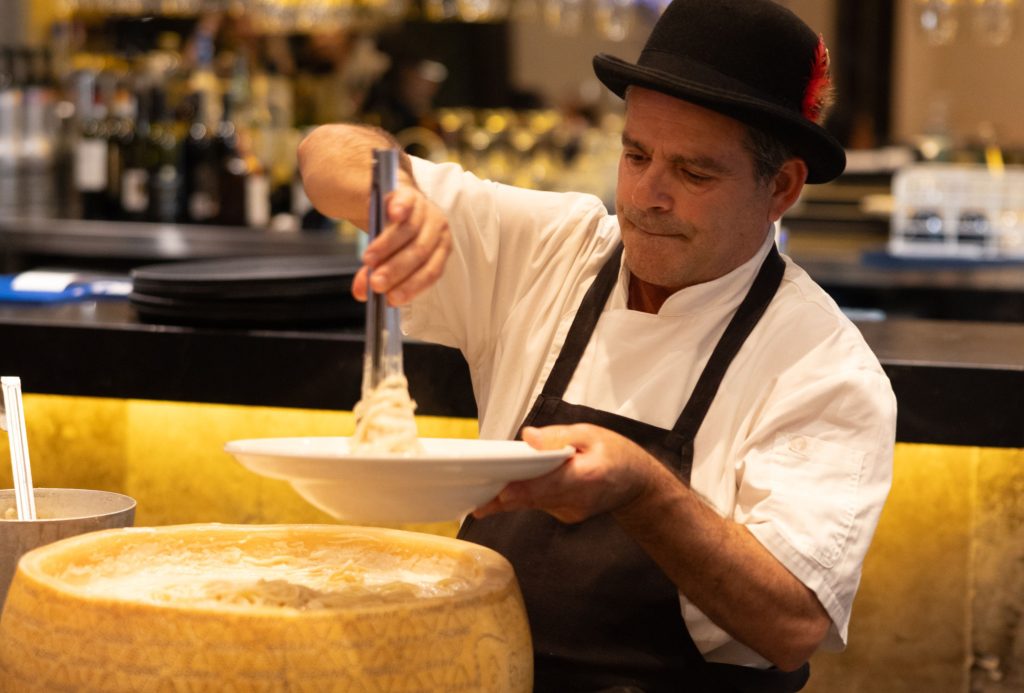 Chef plating creamy pasta from a Grana Padano cheese wheel at Il Verde in Bowen Hills Brisbane